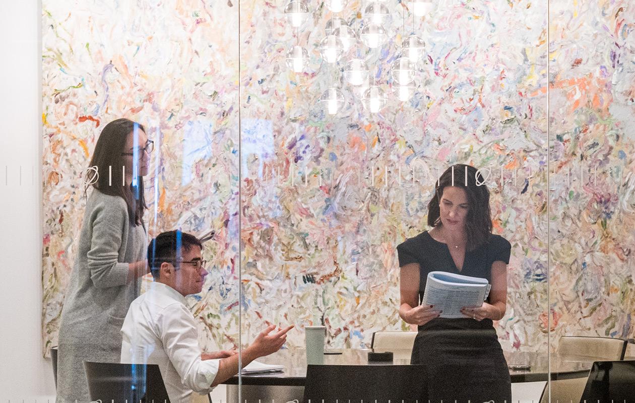 Ares employees in a conference room with a large abstract painting on the wall